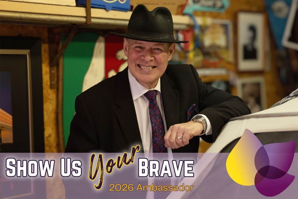 Jim Crichton, Show Us Your Brave 2026 ambassador, smiling beside a car in Windsor-Essex